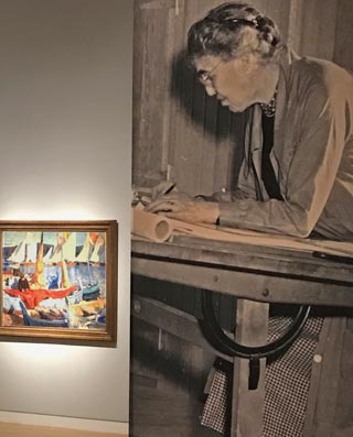 Large exhibition photo of E. Charlton Fortune at her drawing easel alongside her painting,  Drying Sails, St. Tropez
