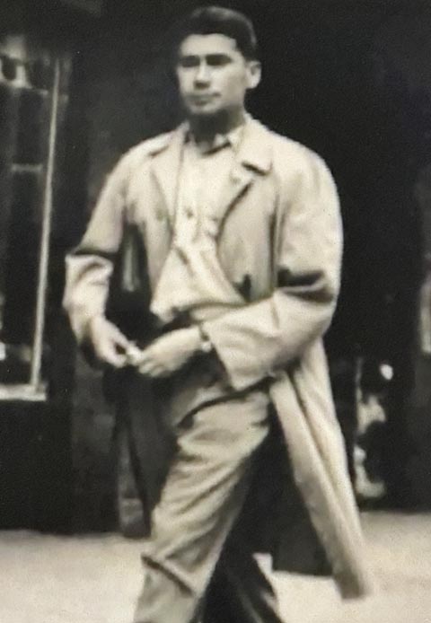Walking down a street, Maurice Lapp in trench coat