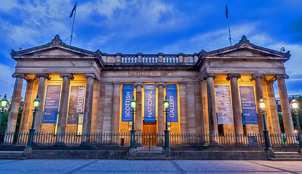 Scottish National Gallery aglow with lights and banners at evening